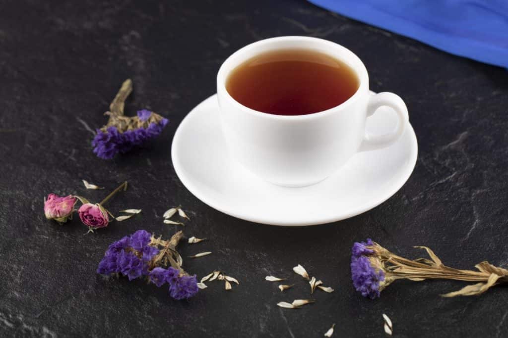 a cup of tea with dried flowers on a black background