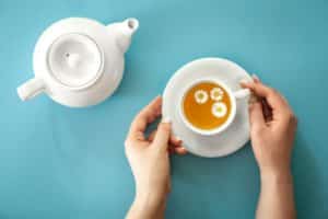 a cup of chamomile tea and a teapot on a blue background, flat lay, minimalism.
